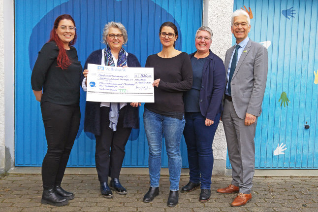 Mitarbeiterinnen und Mitarbeiter von TFZ und Kinderschutzbund Kreisverband Straubing e.V. beim Gruppenbild mit Spendenscheck in der Hand vor blauer Garage