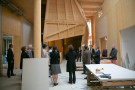 Eine Gruppe von Menschen begutachtet eine Holzkonstruktion in einer Baustelle.