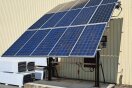 Ein Gerüst mit schräg angebrachten Photovoltaikmodulen steht auf einem betonierten Platz mit Motor