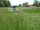 Eine Person mäht mit der Stachelwalze eine Wiese.