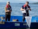 Zwei Männer stehen auf einem Boot im See.