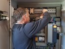 Elektrotechnikerbei der Installation der Komponenten für das Energiemanagementsystem in der Elektroverteilung im Milchviehstall