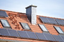 Dachzeile mit Schornstein, Fenstern und Solarzellen