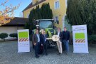Symbolische Schlüsselübergabe eine Claas-Traktor mit vier Herren im Vordergrund.
