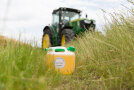 Ein Rapsölkraftstoff-Kanister steht auf einem Feldweg vor einem John Deere