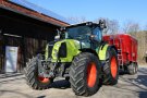 Claas-Traktor mit Anhänger vor landwirtschaftlichem Gebäude mit Dach-PV
