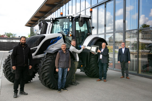 Projektbeteiligte stehen vor einem Traktor neben der Glasfassade des Technikums 