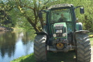 Schlepper steht am Ufer eines Weihers