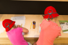 Zwei Mädchen mit roten Hüten malen Bilder
