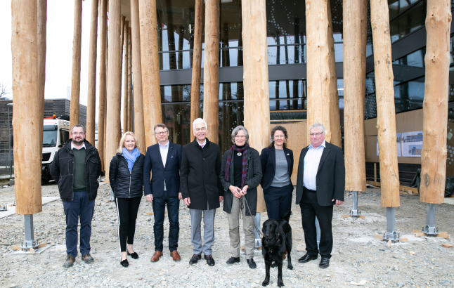 Personen stehen vor Baumstämme auf der Baustelle des NAWAREUM