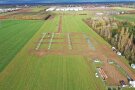 Die Luftaufnahme zeigt eine landwirtschaftliche Fläche, auf der die Gestellpfosten und Modulunterkonstruktionen für eine bodennah nachgeführte und vertikale Agri-PV-Anlage installiert werden. 