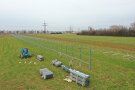 Auf einer landwirtschaftlichen Fläche werden Gestellpfosten und Modulunterkonstruktionen für eine vertikale Agri-PV-Anlage installiert.
