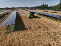Agri-Photovoltaik auf Ackerflächen über die ein Traktor fährt