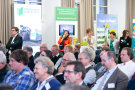 Besucherinnen und Besucher sitzen im Veranstaltungsraum des StMELF und konzentrieren sich auf die Redner.