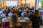Viele Menschen in einem Saal hören einem Vortrag zu