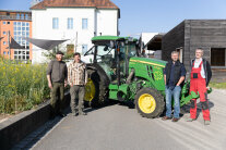 Vier Personen stehen vor einem Traktor