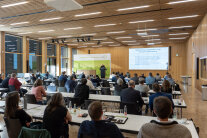 Menschen sitzen in einem Raum und hören einem Redner zu