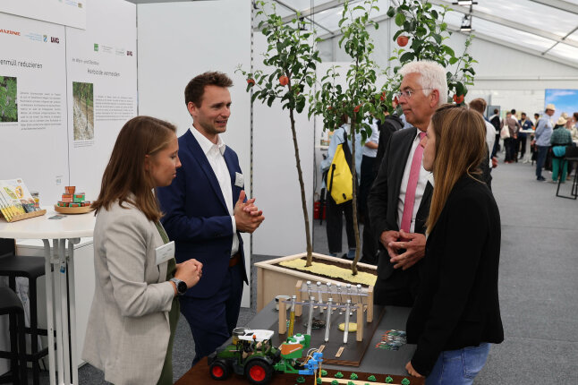 Zwei Frauen und zwei Männer stehen um einen Tisch und sprechen miteinander