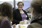 Drei Personen stehen an einem Tisch und unterhalten sich