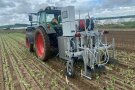 Fendt-Traktor mit Anbau auf einen Acker mit Salatpflänzchen von rechts nach links fahrend