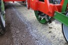 Bildausschnitt einer Rolle zwischen Reifen, die über einen Acker entlang eines gelb aufgetragenen Materialstreifens rollt.