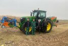 Eine Projektmitarbeiterin und drei Projektmitarbeiter stehen am Acker vor einen John Deere von Anbaugeräten an Front und Heck.