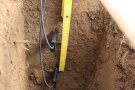 In ausgegrabener Mulde steckt in ca. 35 und 25 cm Tiefe ein Sensor seitlich in der Erde. Ein Meterstab misst.