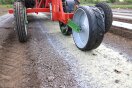 Anbaugerät rollt über Acker entlang eines weiß-gelben Materialstreifens
