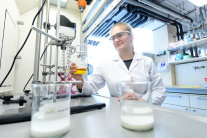 Ein Laborantin experimentiert mit verschiedenen Flüssigkeiten vor einem Luftabzug im Labor.