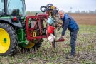 Mann nimmt Bodenproben mit Hilfe eines Traktors und angeschlossenem Gerät