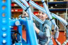 Frau schraubt an Maschine mit blauen Schläuchen