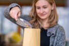 Frau wiegt Samen in eine braune Tüte ein