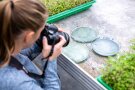 Frau fotografiert drei Petrischalen mit grünlich-blauen Inhalten