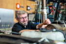 Mann schraubt an Traktor und lächelt dabei in die Kamera
