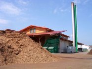 Eine große Heizanlage mit einem Berg aus Hackschnitzeln im Vordergrund