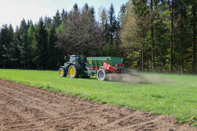 Traktor bringt Asche auf einer Wiese zur Düngung aus