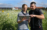 Ein Mann und eine Frau stehen mit einem Tablet in der Hand vor einem Feld